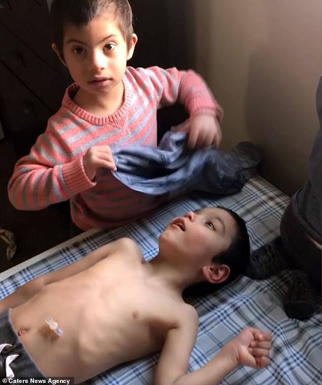 Simon Clark is just four-years-old, yet helps his PE teacher father Jeremy, 33, and nurse mother Nicole, 31, from Utah, feed and dress adopted brothers. He is seen dressingÂ Jon, six, who has Cerebral Palsy