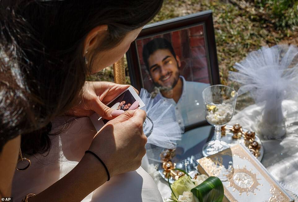 Baluch is seen clutching a photo of her and Sharifi at his grave, which has been covered with flowers and mementos as his headstone isn't finished yet